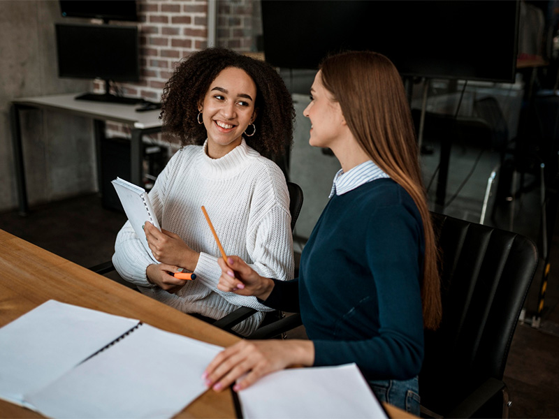 female-colleagues-talking-each-other-during-meeting