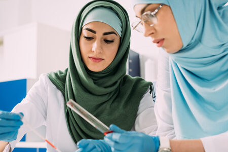 Focused,Female,Muslim,Scientists,Holding,Pipette,And,Glass,Test,Tube